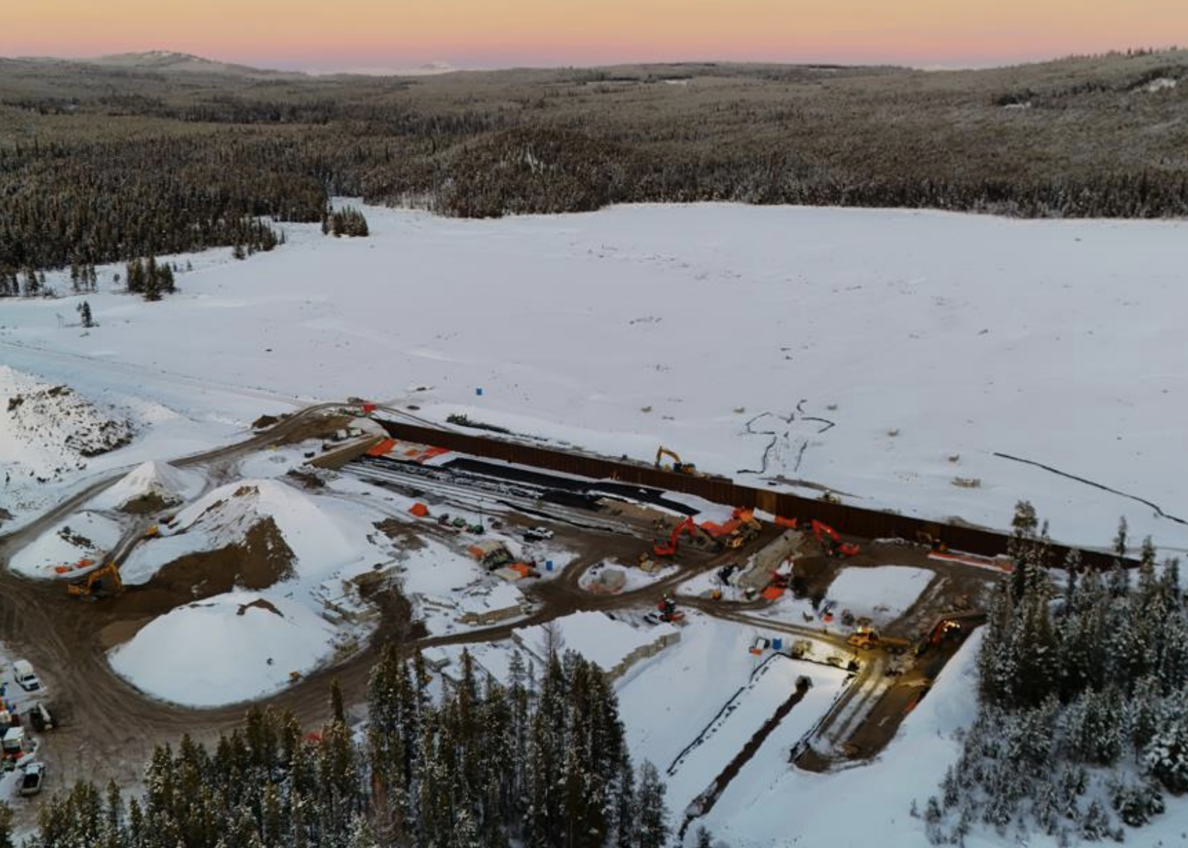 A bird's eye view of a dam construction site in winter.
